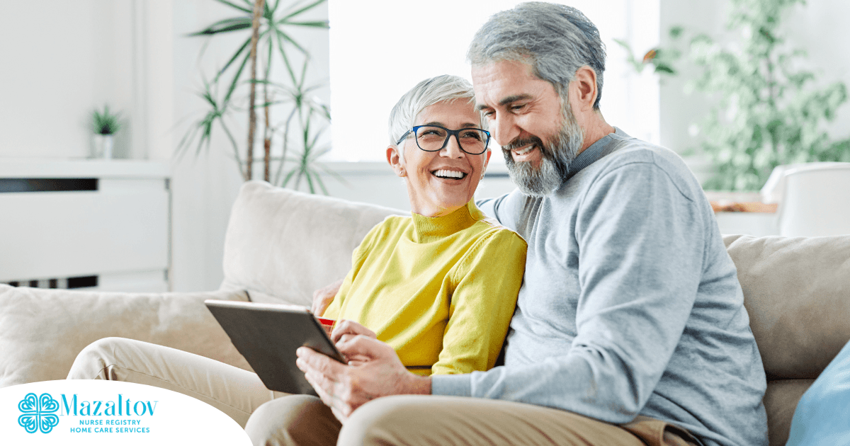 A senior couple smiles while looking at a laptop, showing how online resources can help family caregivers.