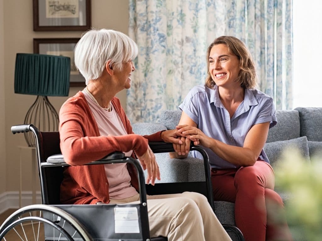 A caregiver and an older woman laughing together at home