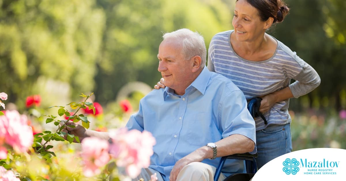 A caregiver brings an older adult with a wheelchair to see some flowers representing how professional caregivers can make outdoor activities accessible.